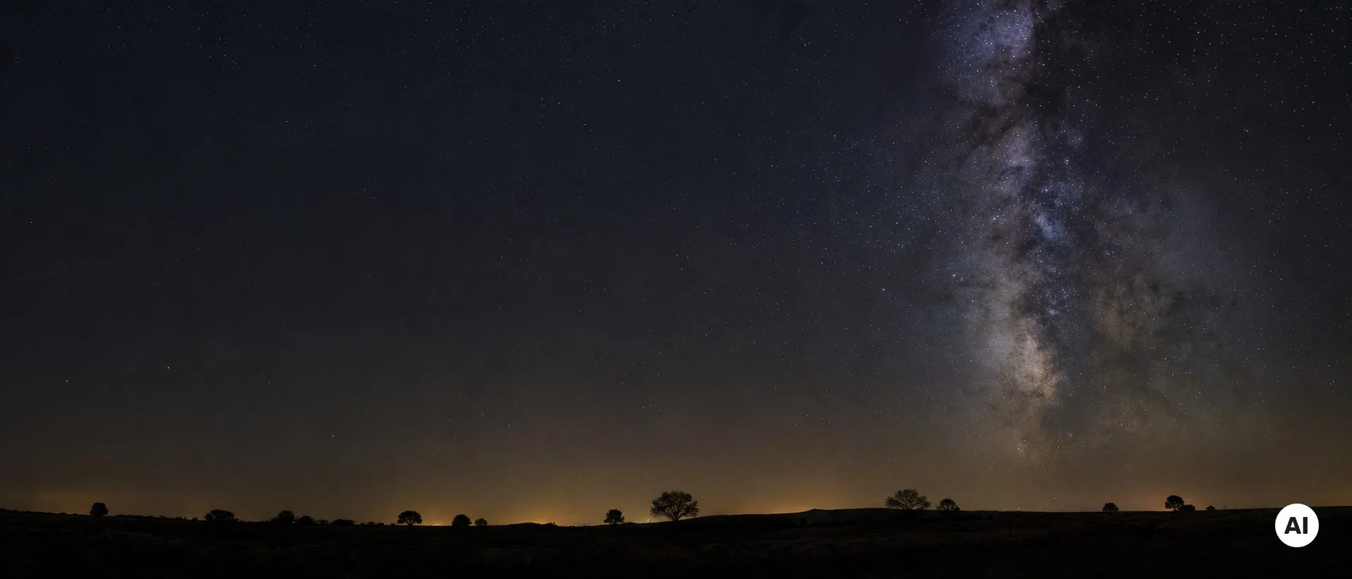 Céu noturno sobre um horizonte baixo e sem luzes, com um ténue brilho quente junto à linha do horizonte.